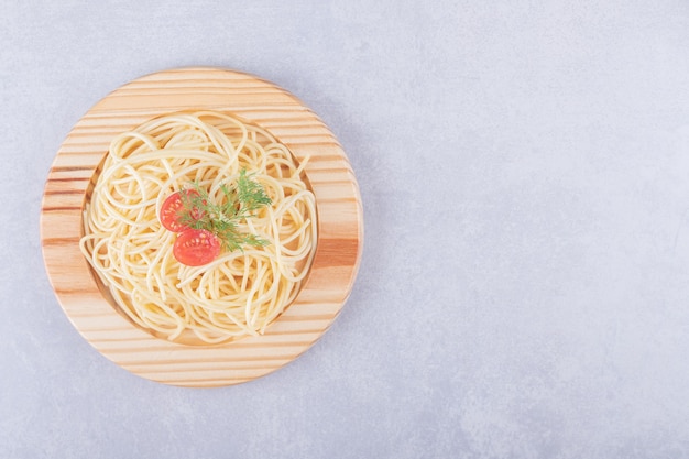 나무 접시에 토마토와 맛있는 삶은 스파게티.