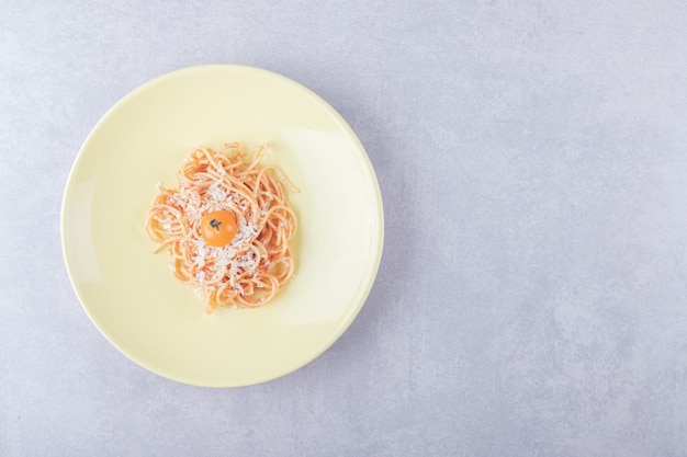 Tasty boiled spaghetti with tomatoes on yellow plate. 