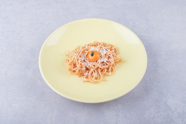 Tasty boiled spaghetti with tomatoes on yellow plate. 