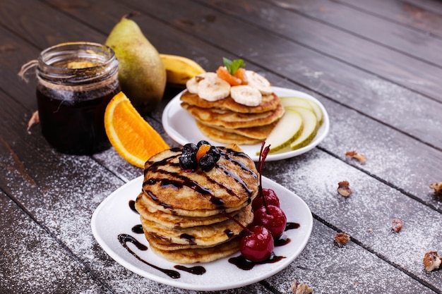 Tasty breakfast. Delicious pancakes covered with chocolate, cherries, bananas and pears