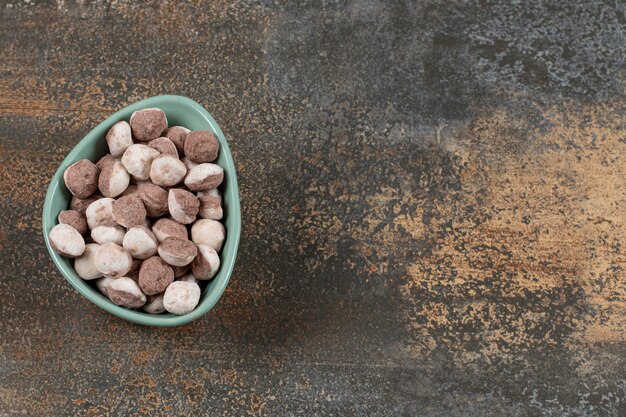 Tasty brown candies in blue bowl.