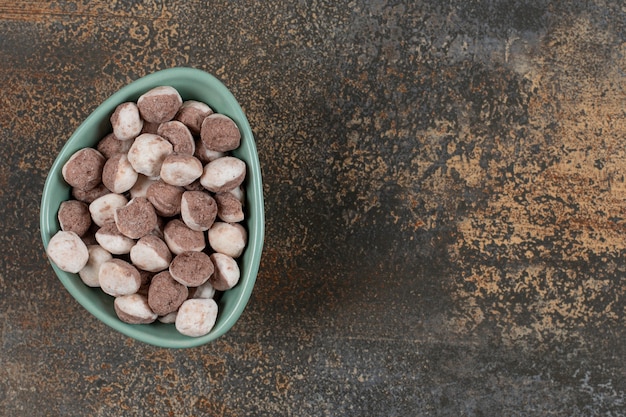 Tasty brown candies in blue bowl.