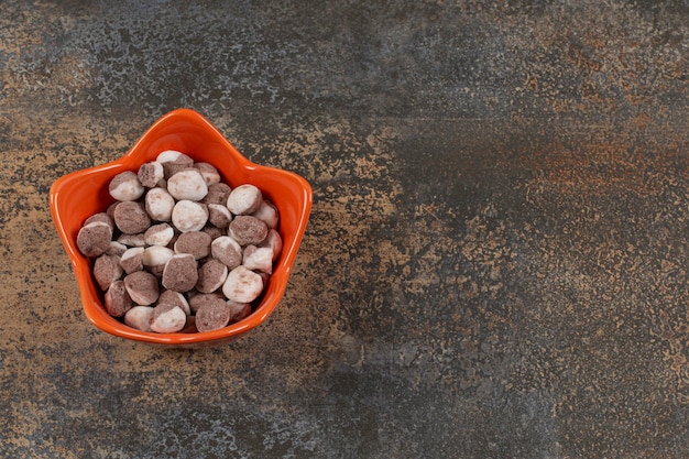 Free photo tasty brown candies in orange bowl.