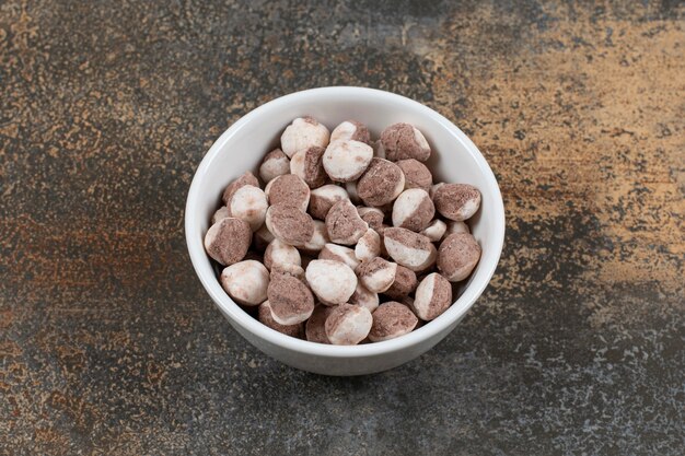 Tasty brown candies in white bowl.