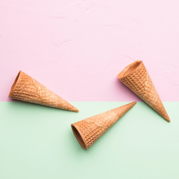 Tasty brown empty ice cream cones on multicolored surface