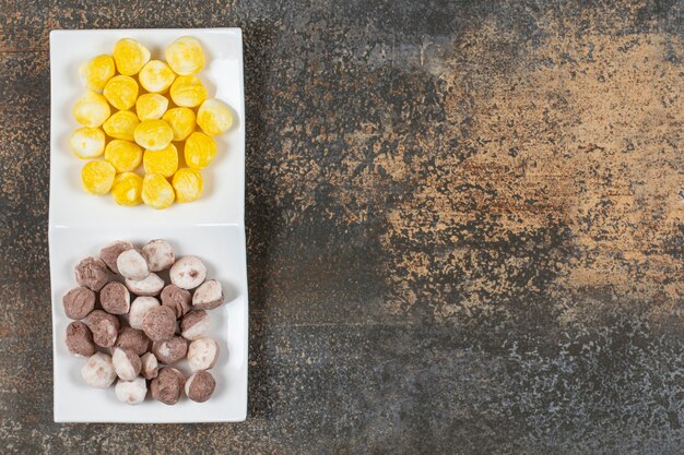 Tasty brown and yellow candies in blue bowl.