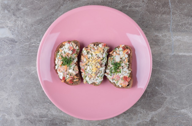 Tasty bruschetta with vegetables on pink plate.