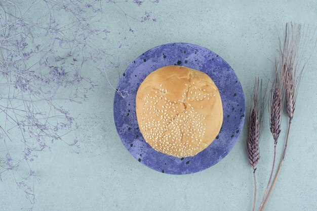 Вкусная булочка для гамбургера с кунжутом на синей тарелке