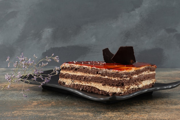 Бесплатное фото Вкусный торт на тарелке с цветком на мраморной поверхности.