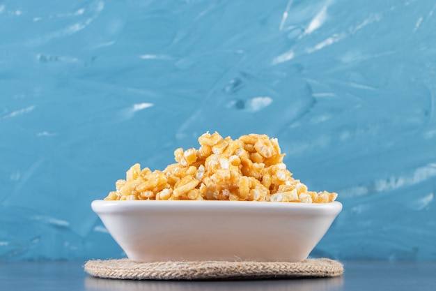 Tasty caramel candies in a bowl on trivet, on the marble surface