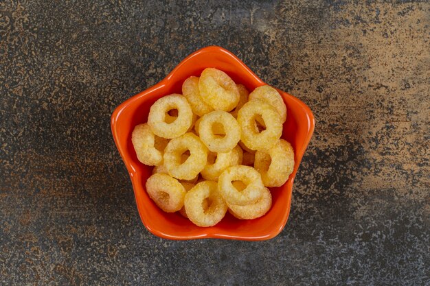 Free photo tasty cereal rings in orange bowl.