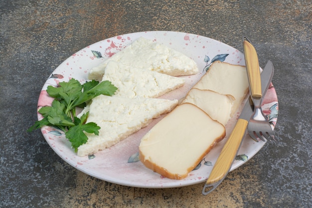 Tasty cheese slices on plate with cutlery.