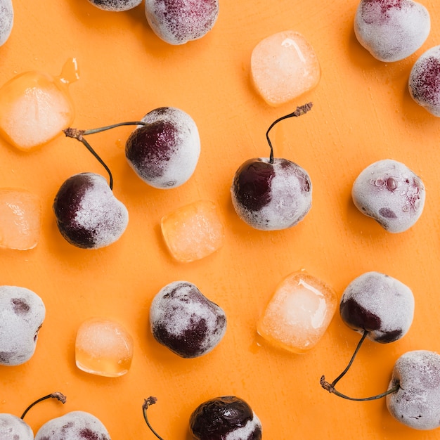 Tasty cherry and ice cubes on orange background