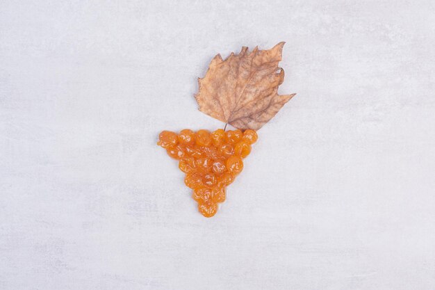 Tasty cherry jam with leaf on white table .