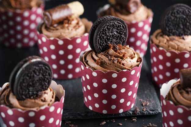 Tasty chocolate muffins cupcakes with buttercream decorated in cups. Closeup