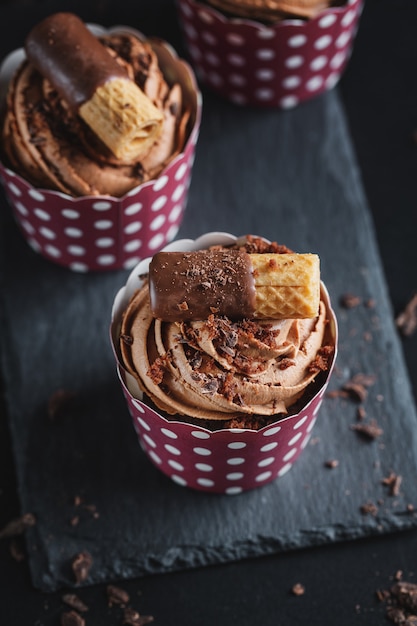 Tasty chocolate muffins cupcakes with buttercream decorated in cups. Closeup