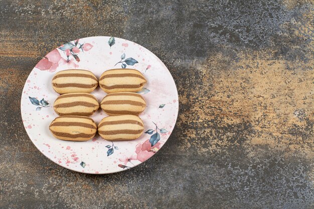 Tasty chocolate striped biscuits on colorful plate.