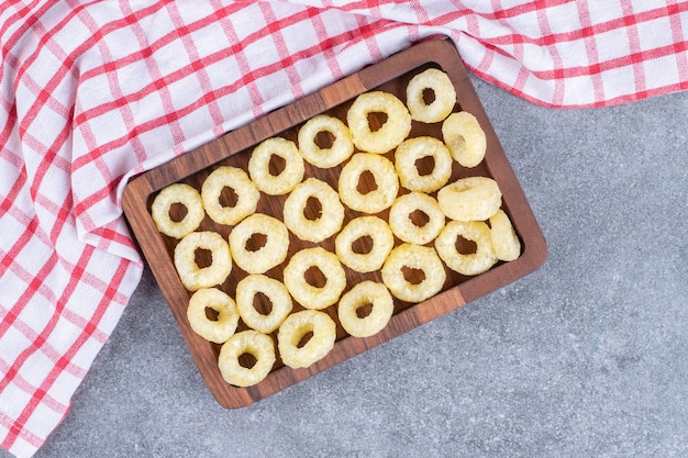 Tasty circle crackers on wooden plate with tablecloth