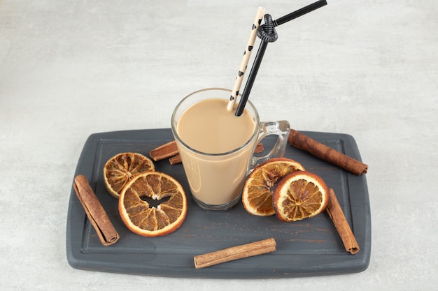 Вкусный кофе, палочки корицы и дольки апельсина на темной тарелке