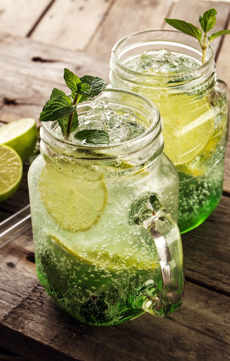 Free Photo tasty cold fresh drink lemonade with lemon, mint, ice and lime in glass on wooden table. closeup.