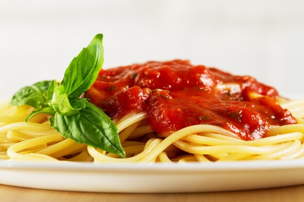 Вкусные разноцветные аппетитные спагетти итальянской пасты с томатным соусом болоньезе и свежим базиликом. Крупный план.