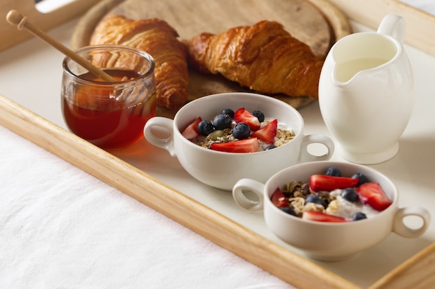 Вкусный красочный завтрак с овсянкой, йогурт, клубника, черника, мед и молоко на белом фоне. Завтрак в постель. Копирование пространства. Вид сверху.