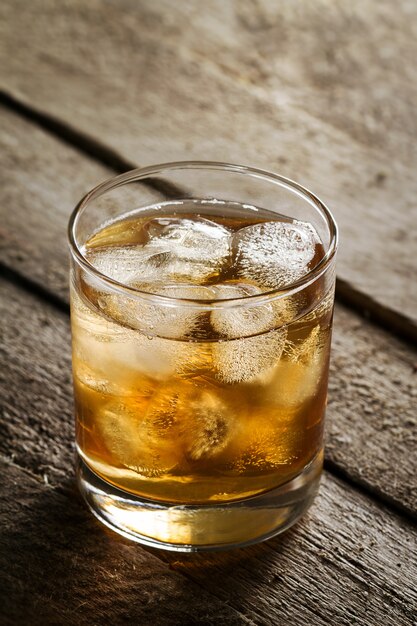 Tasty Colorful Cold Alcohol Drink Whiskey with Ice in Glass on Wooden Table.