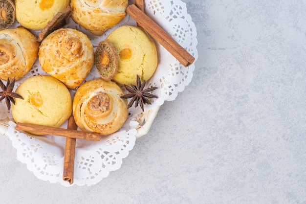 Free photo tasty cookies, cinnamons dried kiwi and anise in a wicker basket, on the marble background.