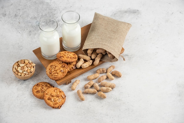 Tasty cookies with organic peanuts and honey with glass of milk on wooden board. 