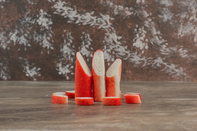 Tasty crab sticks on marble table .