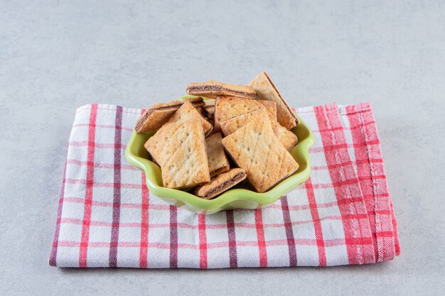 Tasty cracker biscuits filled with chocolate in green bowl.