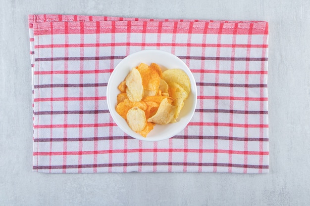 하얀 그릇에 식탁보를 얹은 맛있는 바삭한 칩.