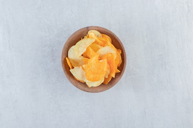 Free photo tasty crispy chips placed in wooden bowl on stone.