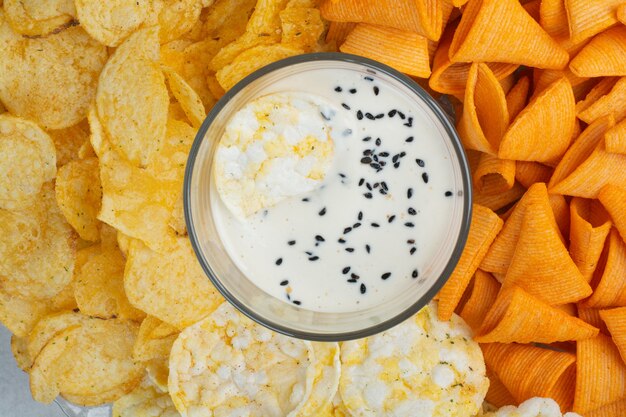 Tasty crucnhy potato chips with yogurt on white background. High quality photo