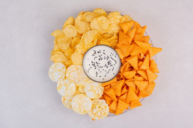 Tasty crucnhy potato chips with yogurt on white background. High quality photo