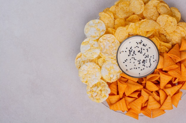 Tasty crucnhy potato chips with yogurt on white background. High quality photo