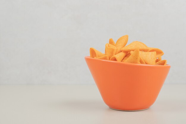 Tasty crunchy chips in orange bowl
