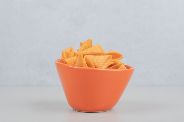 Tasty crunchy chips in orange bowl