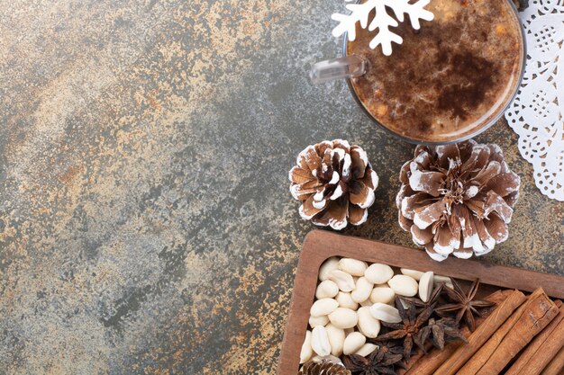 Tasty cup of cocoa with cinnamon sticks and pinecones on marble background. High quality photo