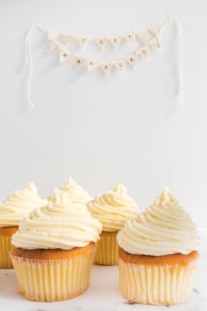 Tasty cupcakes and just married bunting on white background