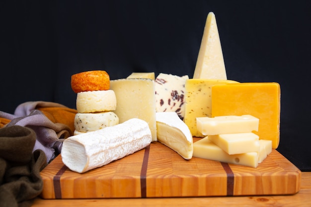 Tasty different cheeses laying on wooden board