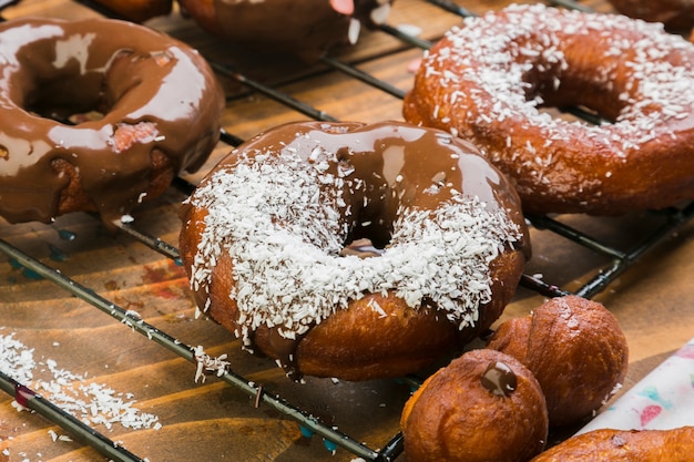 Tasty donuts with chocolate syrup and grated coconut on baking tray