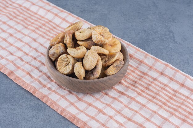 Tasty dried fruits in bowl on the towel, on the marble background. 