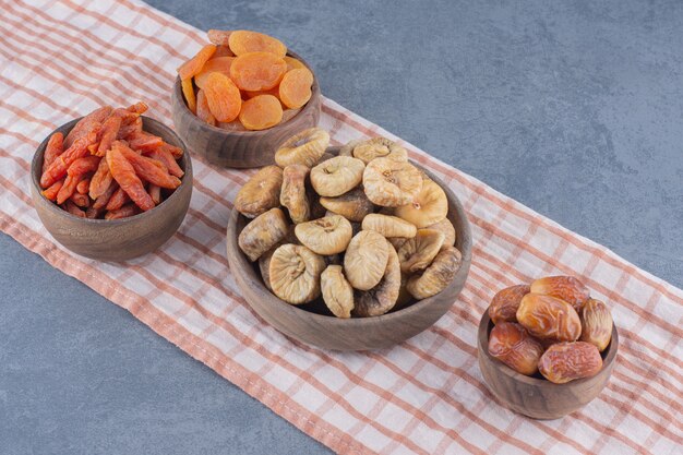 Tasty dried fruits in bowls on the towel, on the marble background. 