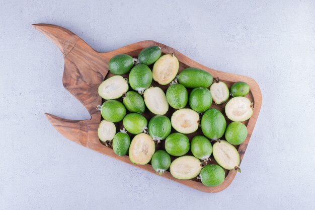 Tasty feijoas bundled up in a wooden tray on marble background. High quality photo