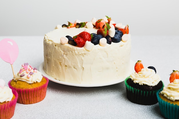 Tasty fresh cake with berries and set of little muffins