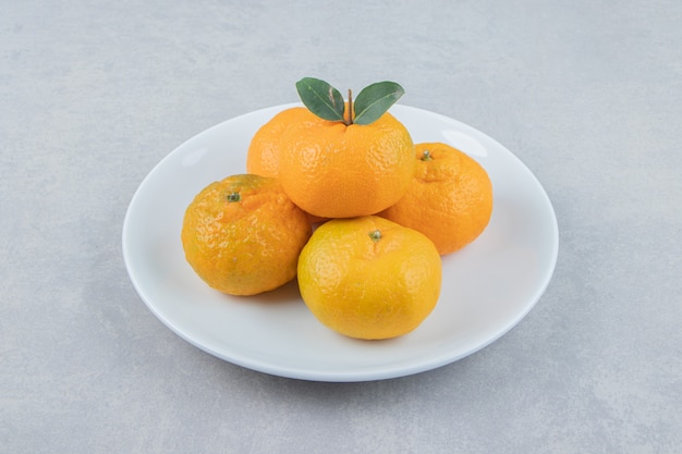 Tasty fresh tangerines on white plate