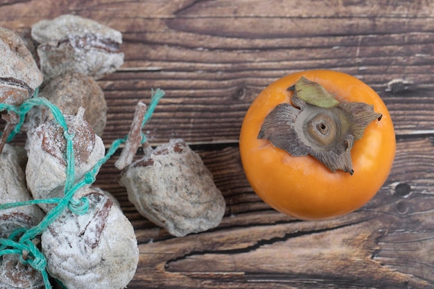 Tasty fuyu persimmons and dried persimmons on wooden surface