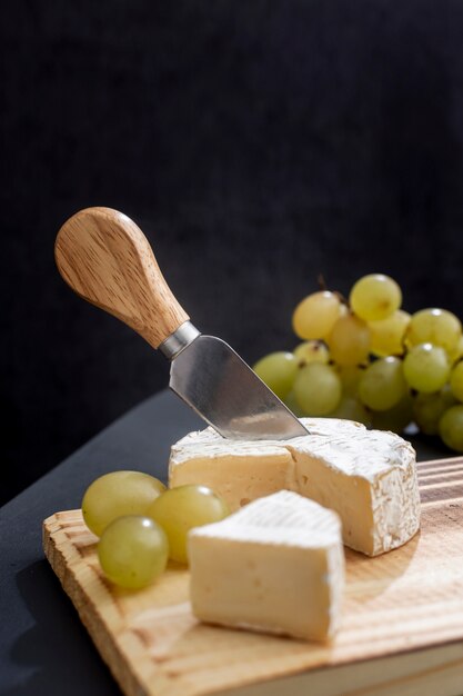 Tasty grapes with brie cheese on a board