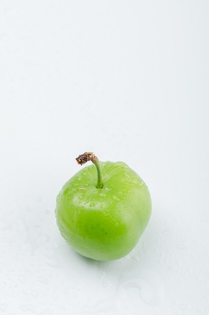Tasty green plum high angle view on a white wall